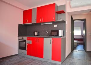 a kitchen with red cabinets and a microwave at Visito Aparthouse in Sofia