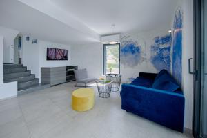 a living room with a blue couch and a yellow stool at Villa Periska Komiža in Komiža