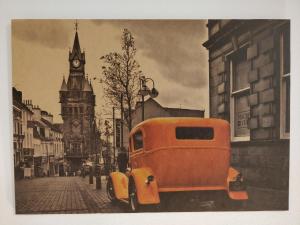 Ein orangefarbenes Auto parkt in einer Stadtstraße mit einem Uhrturm in der Unterkunft Savski Gaj in Zagreb