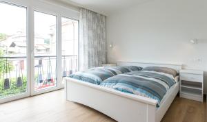 a white bedroom with a bed and a large window at Apartements Kaschitz in Pörtschach am Wörthersee