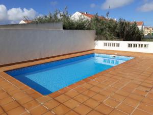 a swimming pool with a tile floor and a fence at Apartments Baleal: Balconies and Pool in Ferrel