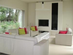a living room with white furniture and a flat screen tv at Duinpaviljoen in Koksijde