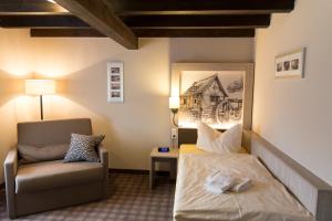 a hotel room with a bed and a chair at Hotel Garni Mühlenhof in Wusterhausen