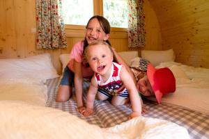 Zwei Mädchen und ein Baby auf dem Bett in der Unterkunft Fasslhütte in Murau