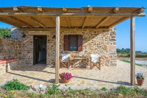 un edificio in pietra con pergolato in legno su un patio di The Stone House a Potamós