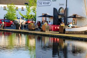 a group of people sitting at tables next to a river at The Wharf Stourport in Stourport