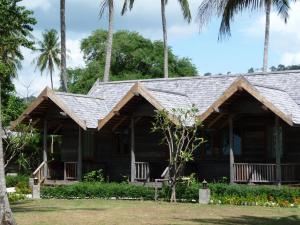 een houten huis met palmbomen ervoor bij New Ozone Resort & Spa in Koh Lanta
