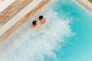 a man and a woman are in a swimming pool at Hotel Eden Spiez in Spiez