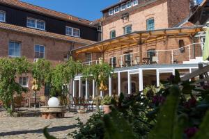 un grand bâtiment en briques avec une cour dotée de tables et de chaises dans l'établissement Hotel Garni Mühlenhof, à Wusterhausen