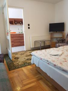 ハイドゥソボスローにあるGyöngy és Miki Apartmanokのベッド付きの部屋、ドア付きのキッチンが備わる客室です。