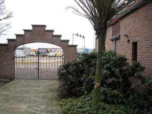 a gate in a brick building with a tree in front of it at Hotel Plaza in Lommel