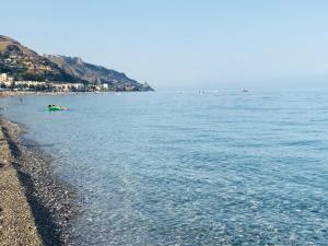 a beach with people swimming in the water at Taonasi Mazzeo Apartment in Mazzeo