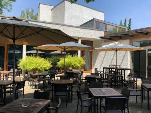 een patio met tafels, stoelen en parasols bij Akademie der Dioezese in Stuttgart