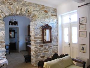 Luxury 100 m2 house in the centre of Naxos في Dhamariónas: غرفة معيشة مع جدار حجري وأريكة
