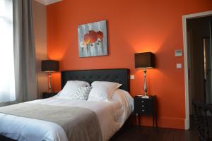 1 dormitorio con paredes de color naranja y 1 cama con 2 lámparas en Villa Vesone, en Périgueux
