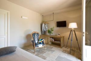 a bedroom with a bed and a chair and a television at Agriturismo Tra gli Ulivi, Chiappini in Bolgheri