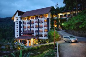 a car driving down a road in front of a hotel at The Grand Hill Resort-Hotel in Puncak