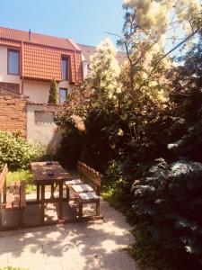 a picnic table and benches in front of a house at Rózsakert Panzió in Nyíregyháza