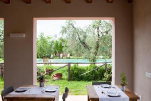 una sala da pranzo con due tavoli e una grande finestra di Agriturismo Tra gli Ulivi, Chiappini a Bolgheri