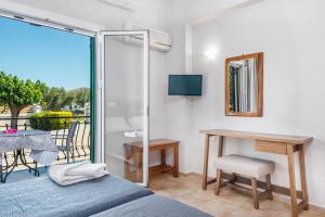 a bedroom with a bed and a table and a balcony at Villaggio Verde in Laganas