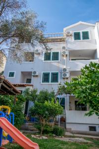 a white building with a playground in front of it at Apartman Zenta in Petrovac na Moru