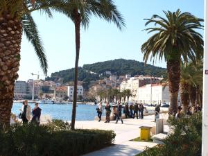 a group of people walking on a sidewalk near the water at Damira Rooms in Split