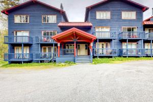 a large blue house with a porch and balcony at Brighton Condo #209 in Girdwood