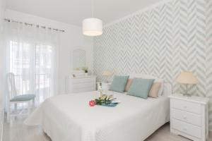 Un dormitorio blanco con una cama blanca con flores. en Ericeira T2 Navegantes Apartment, en Ericeira