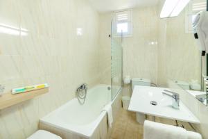 a bathroom with a sink and a tub and a toilet at RVHotels Avenida in Tossa de Mar