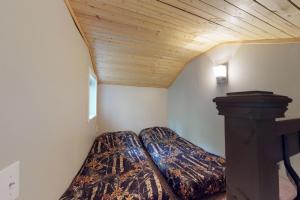 une chambre avec deux lits et un plafond en bois dans l'établissement Loveland Cottage, à Girdwood