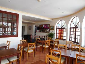 ein Restaurant mit Holztischen, Stühlen und Fenstern in der Unterkunft Agua Marinha ROSA- Hotel in Albufeira