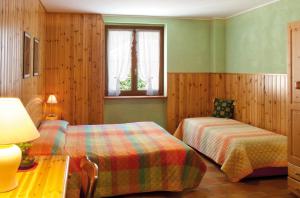a bedroom with two beds and a table and a window at Hotel Corona in Branzi