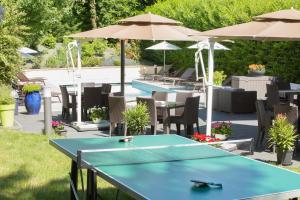 a ping pong table and chairs and umbrellas at Logis Hotel Le Petit Casset in La Boisse