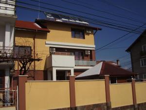 a yellow and white building behind a fence at Guest House Goranovi in Velingrad