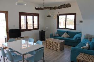 Una sala de estar con un sofá azul y una mesa. en Fteroma Villa, en Pissouri