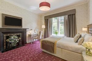 a hotel room with a bed and a fireplace at Burn How Garden House Hotel in Bowness-on-Windermere