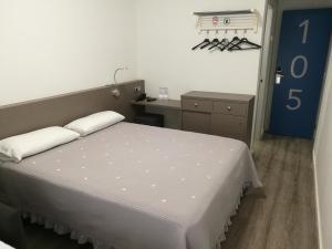 um quarto com uma grande cama branca e uma secretária em Hotel Alguer Camp Nou em Barcelona