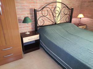 a bedroom with a green bed and a night stand with a lamp at Cabañas Soleado Villa Cura Brochero in Villa Cura Brochero