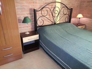 1 dormitorio con cama verde y mesita de noche con lámpara en Cabañas Soleado Villa Cura Brochero en Villa Cura Brochero