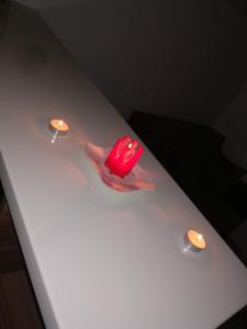 un objet rouge assis sur une table blanche avec deux lumières dans l'établissement Apartman "Vienna", à Sokobanja