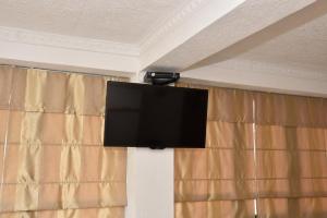 a flat screen tv on a wall with curtains at Guest House Evropa in Ulcinj