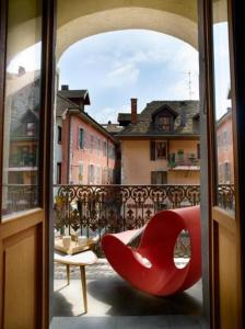 un fauteuil rouge installé au-dessus du balcon dans l'établissement "Un Lieu Unique" Le Lodge et le Dolce, à Annecy