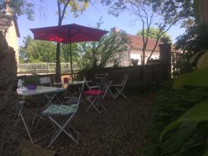 a patio with a table and chairs and an umbrella at Chambres d'hotes La Chaumiere in Coulonges