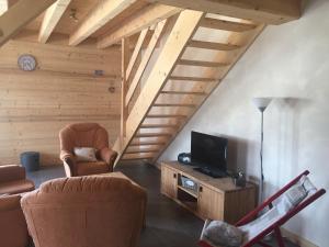Le Bouilly的住宿－Au cœur du bois，客厅配有两把椅子和电视