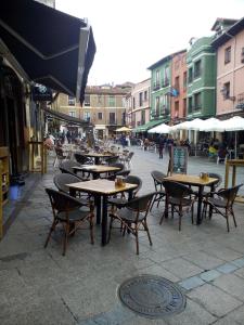 een groep tafels en stoelen in een stadsstraat bij Apartamentos Corazón del Húmedo in León