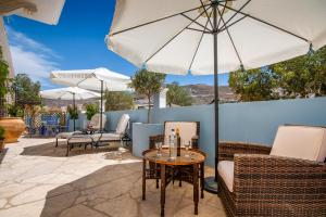 a patio with chairs and a table with an umbrella at Villa Galanis in Symi