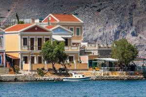 a small boat in the water in front of houses at Villa Galanis in Symi