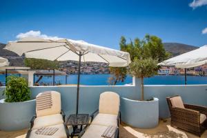 a patio with tables and chairs and an umbrella at Villa Galanis in Symi