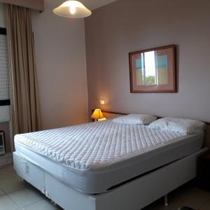 1 dormitorio con cama blanca y espejo en la pared en BARRA BELLA PRAIA RESIDENCE - Internet 350mb -TV -AR - Vista mar - Piscina climatizada- HomeOficce, en Río de Janeiro