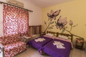 ein Schlafzimmer mit 2 Betten und einem Sofa und Blumen an der Wand in der Unterkunft Studios Ifigenia in Skala Potamias